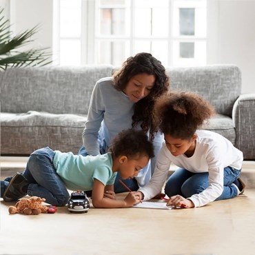 Woman sitting in clean living room playing with her two children