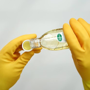 Zoflora being poured into cap held by yellow rubber gloves